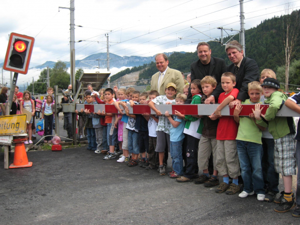 Die Kinder der Volksschule Bruckhäusl entfernten gemeinsam mit (von links) Kirchbichls Bgm. Herbert Rieder, ÖBB Projektleiter Günter Oberhauser und Wörgls Bgm. Arno Abler den Bahnschranken bei der Haltestelle Bruckhäusl