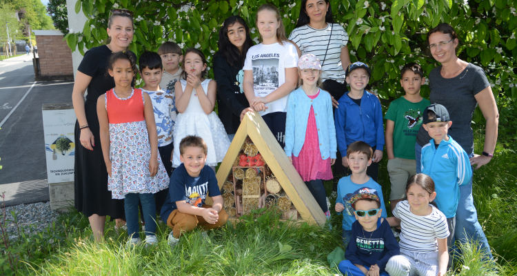 Die Kinder der Mehrstufenklasse B der Volksschule zwei mit ihren Lehrerinnen beim Aufstellen des neuen Insektenhotels im Wörgler Freigarten